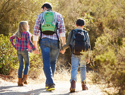 dad and children hiking // Photo by monkeybusinessimages/iStock/Getty Images Plus/Getty Images dad and children holding hands and hiking in the woods